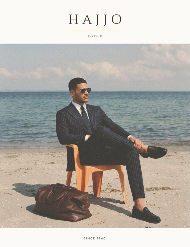 The cover of the Hajjo Group book: a man in a navy chalk stripe suit on a chair at the water's edge.