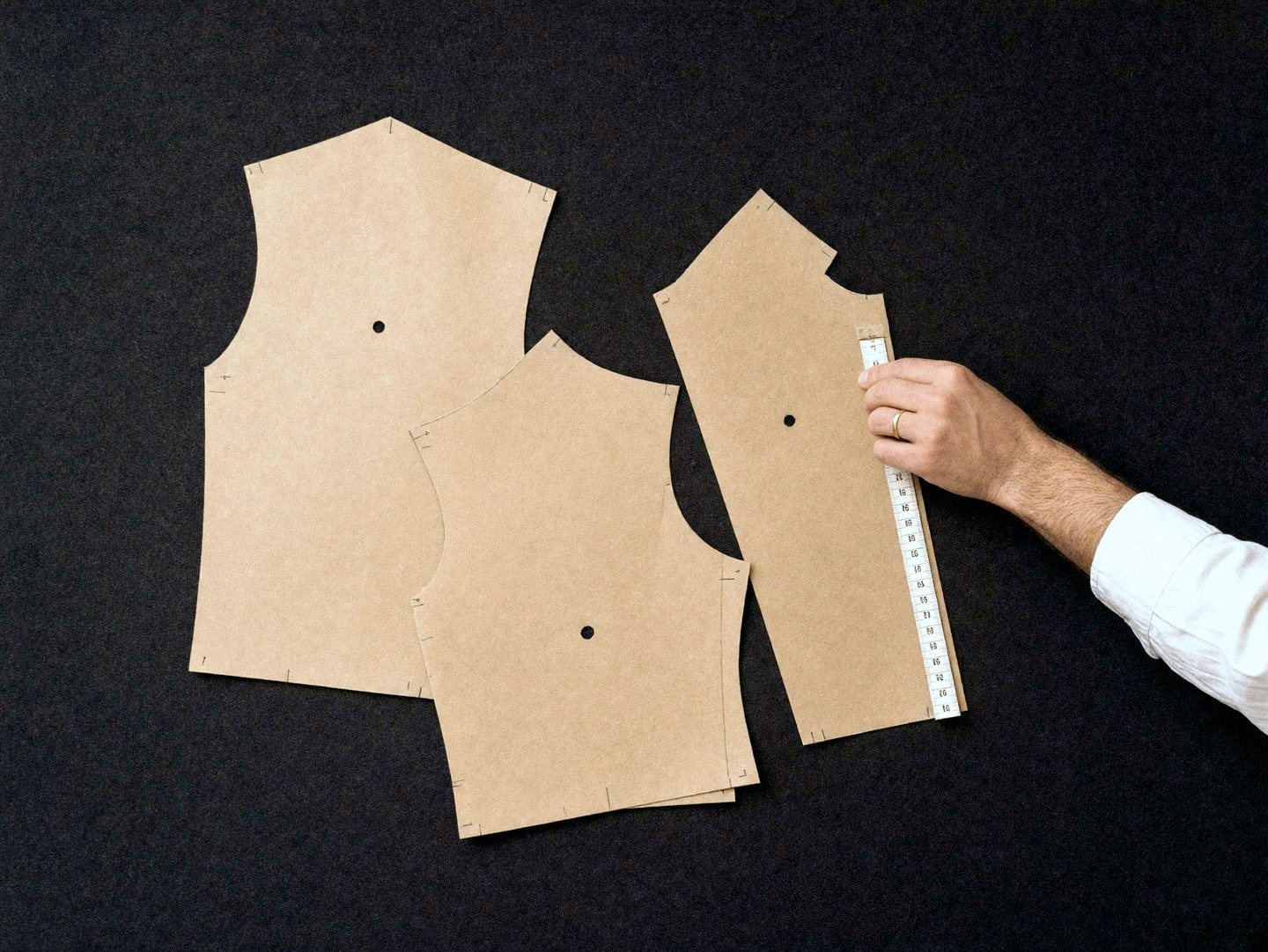 Paper pattern pieces on navy cloth with a tape measure